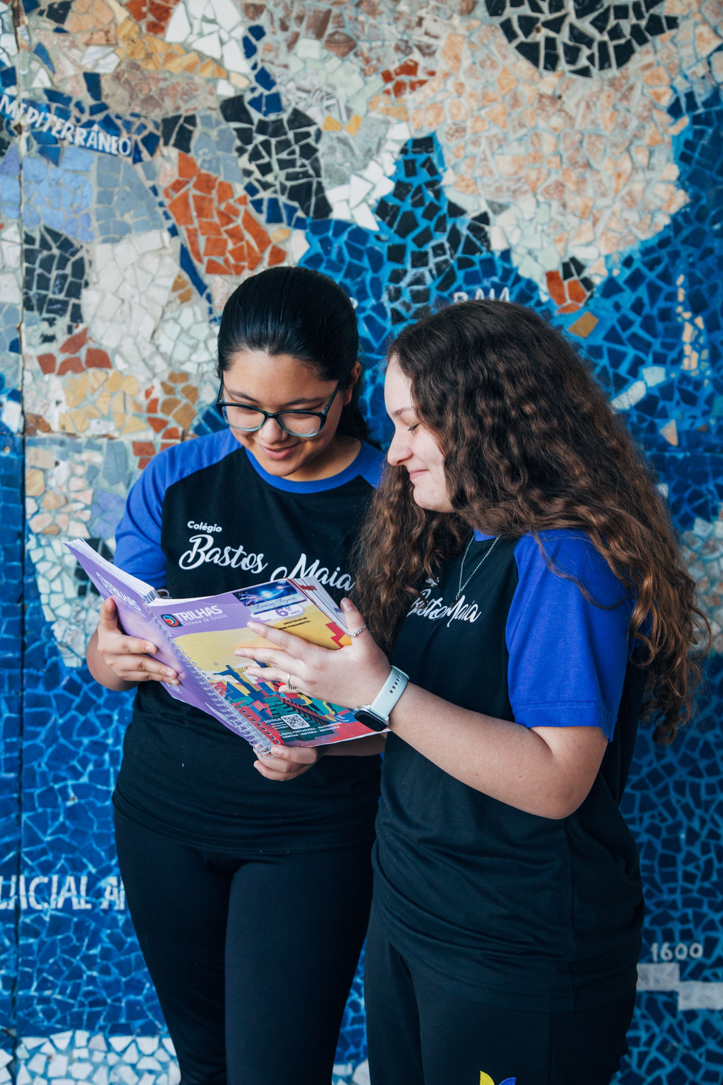 Alunas lêem livro juntas no pátio - Escola Bem Melhor